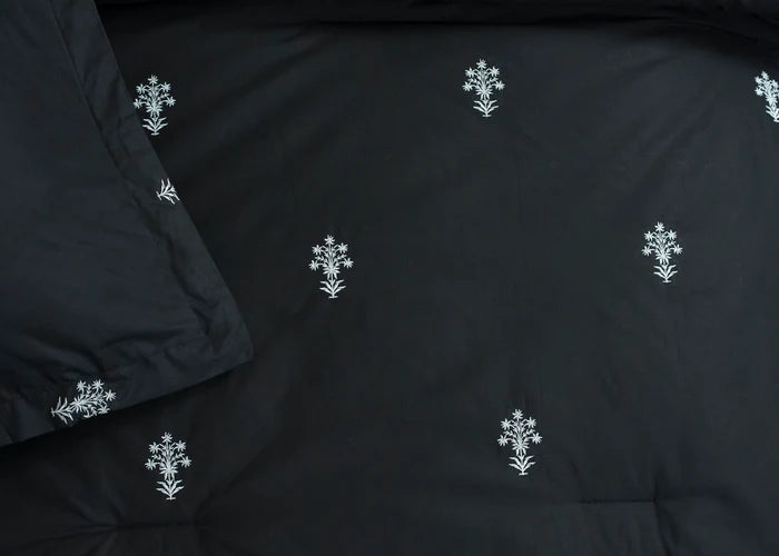 Black comforter fabric close-up with scattered white floral cross pattern