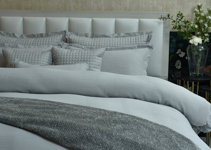 Grey and white duvet cover set with matching quilted pillow shams and folded throw