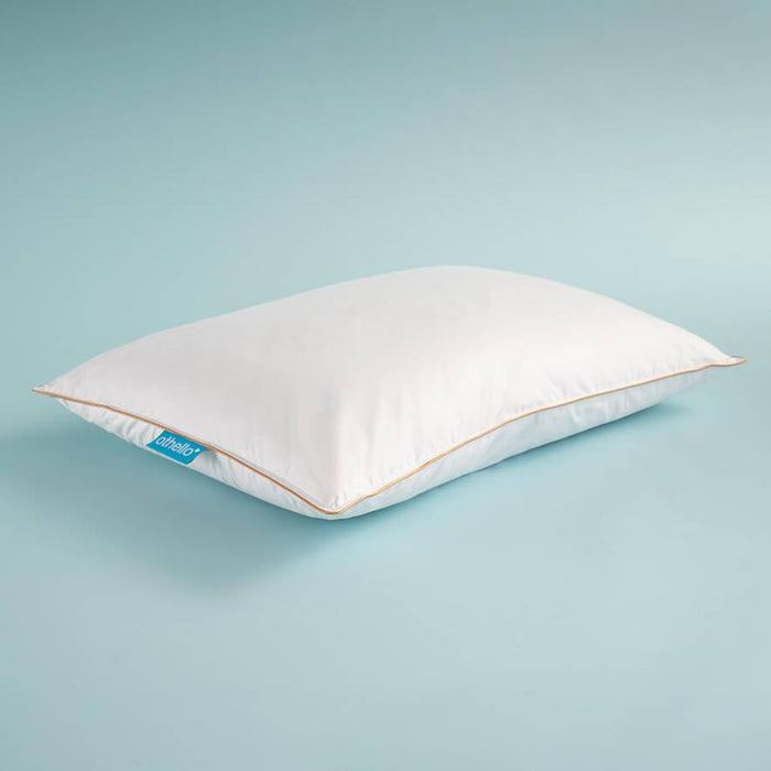 White down-filled pillow, angled view, with orange piping and blue brand tag.