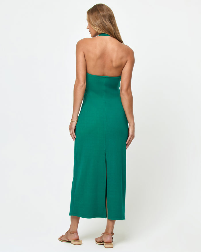 Back view of a model wearing the LSPACE La Femme Dress in Isle on a white background, showing the open back with halter tie and center back slit of the emerald green ribbed knit maxi dress.