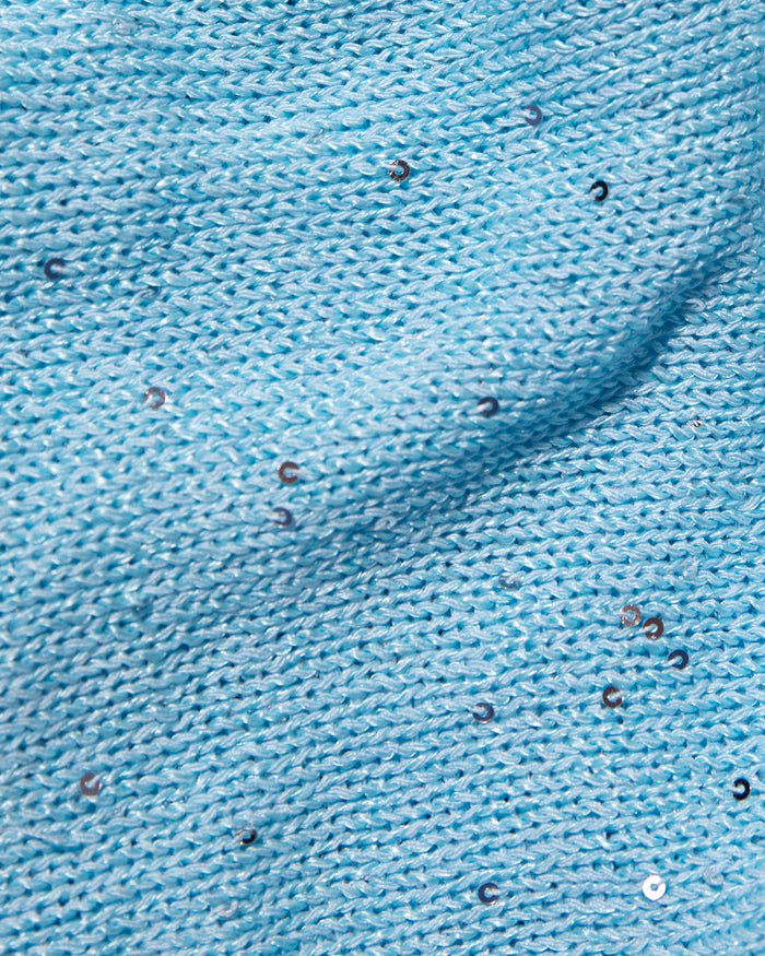 A close-up of light blue knit fabric with scattered small reflective sequins.
