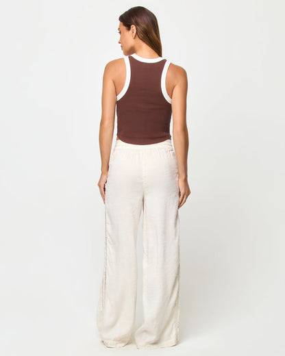 Back view of a model wearing the LSPACE Ash Tank in espresso-cream, showing the racerback detail with cream contrast trim against the espresso brown body, styled with cream wide-leg drawstring pants.