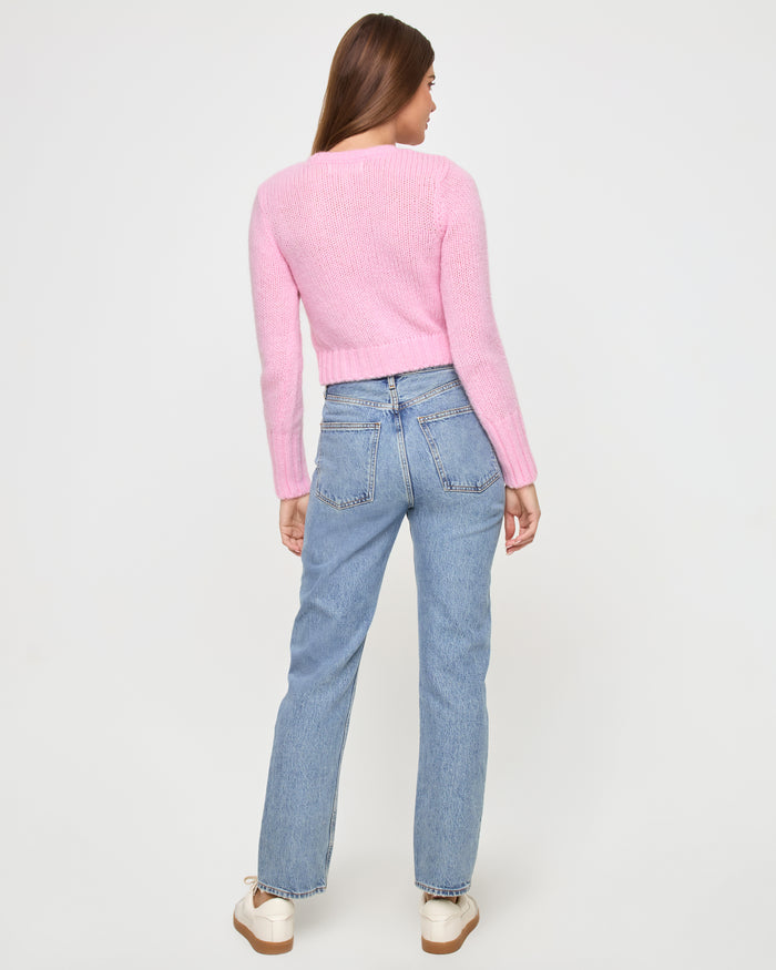 Back view of a model wearing the LSPACE Brynn Cardigan in rosewater, showing the cropped knit silhouette and long sleeves.