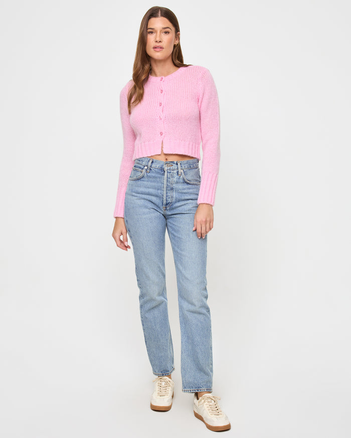 Front view of a model wearing the LSPACE Brynn Cardigan in rosewater, a cropped pink knit cardigan with button-front closure, styled with jeans.