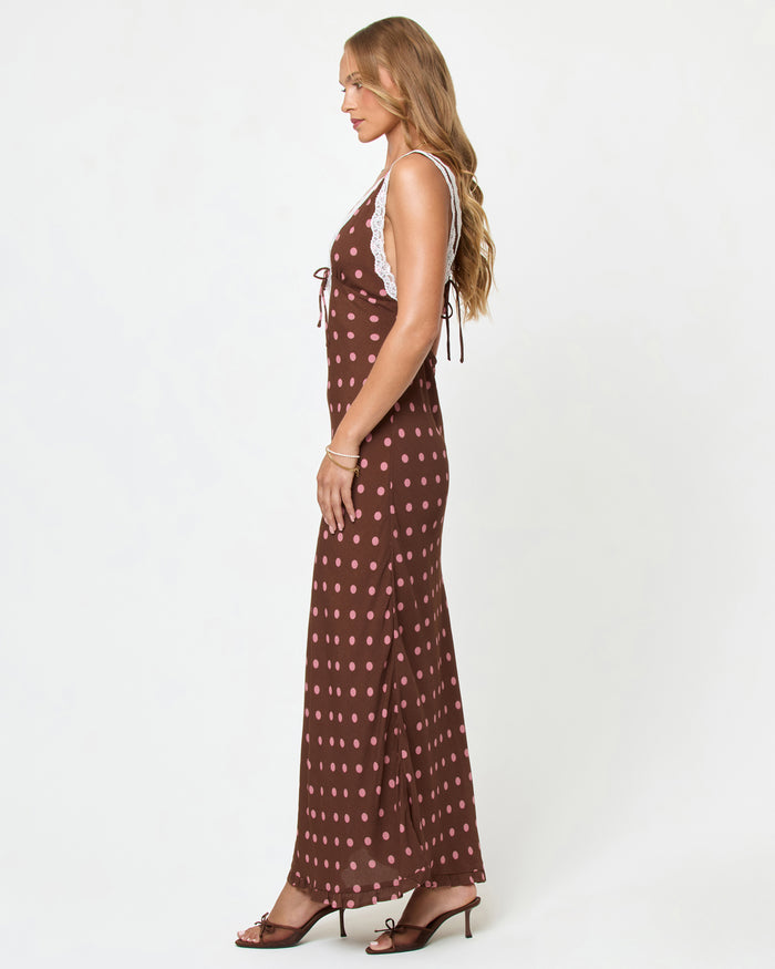 Side view of a model wearing the LSPACE Eyes On You Maxi in Alotta Polka Dot on a white background, showing the full-length silhouette of the brown polka dot maxi dress.