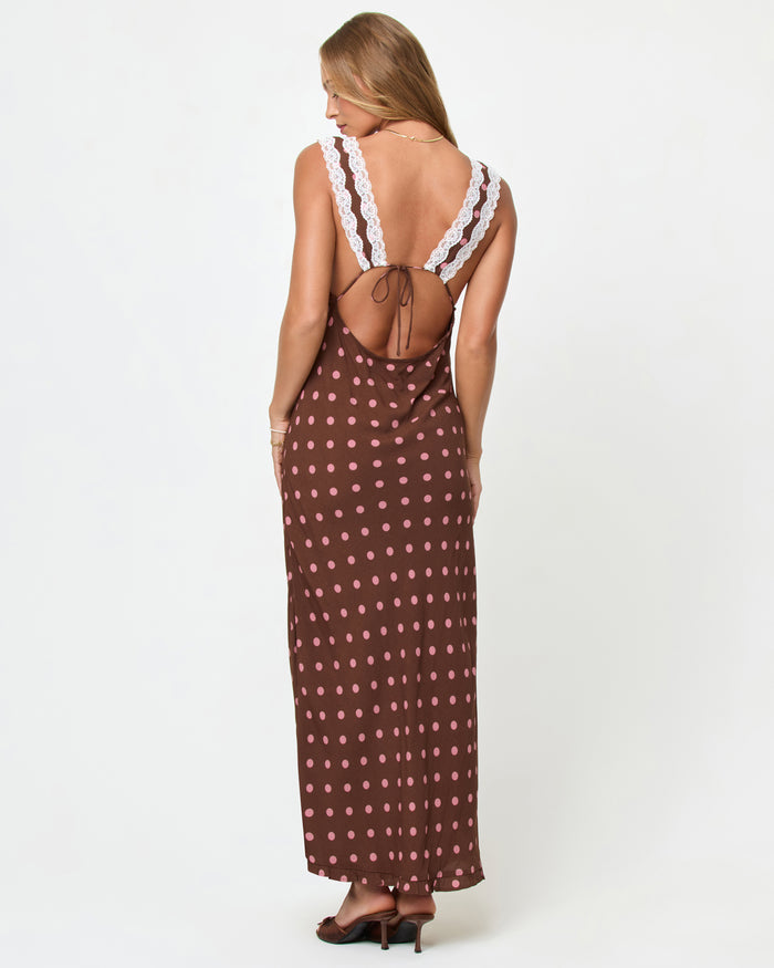 Back view of a model wearing the LSPACE Eyes On You Maxi in Alotta Polka Dot on a white background, showing the open-back lace strap design and full-length skirt with side slit.