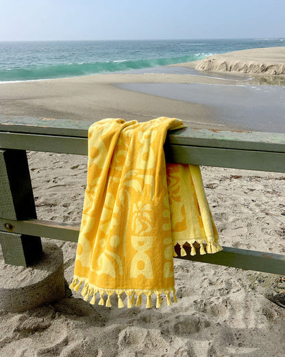 LSPACE Holiday In The Sun towel, off-model flat lay draped on a railing at the beach.