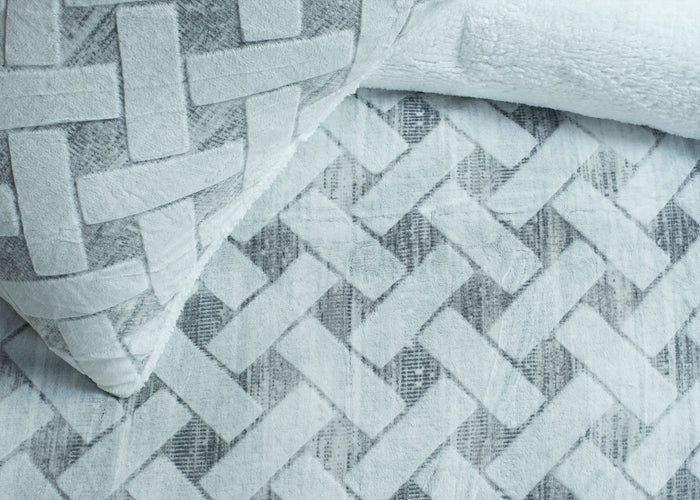 Close-up of quilted chevron pattern bedding fabric with raised geometric texture