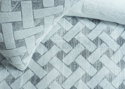 Close-up of quilted chevron pattern bedding fabric with raised geometric texture