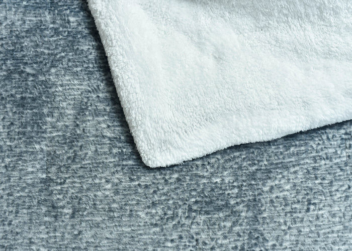 Light grey and lighter flannel bedding layers with soft fuzzy texture close-up