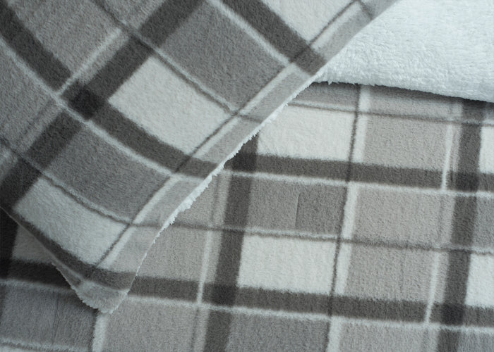 Close-up of grey-and-white plaid comforter fabric with stitched seams