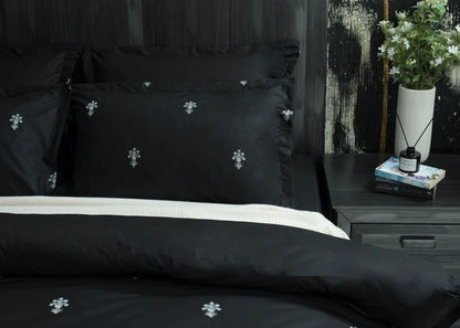6-piece black comforter set with white floral cross motif, stacked pillows detail