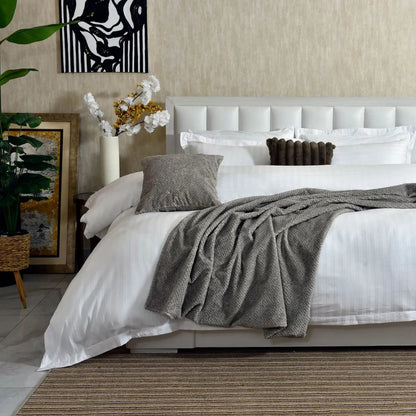 White pinstripe duvet cover with folded gray throw and decorative pillows
