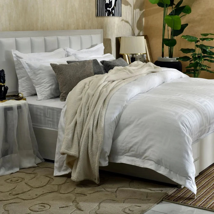 White duvet cover set with gray pillows and beige throw blanket, bed view