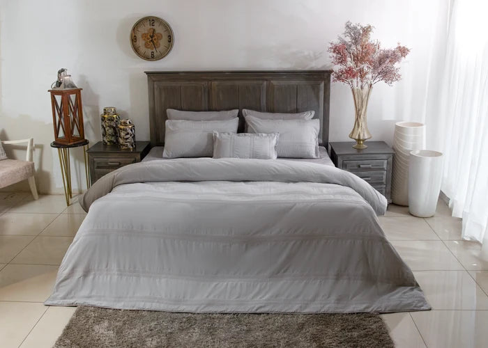 Grey duvet cover set with pillow shams and layered pillows, neatly arranged