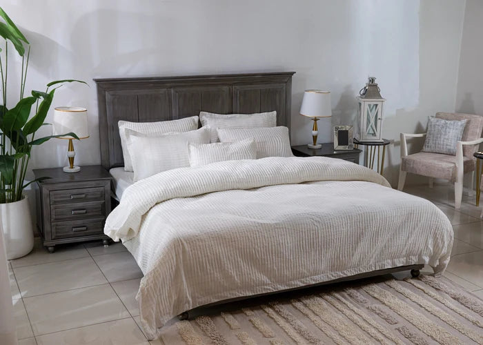 Off-white striped duvet cover with layered pillows on a bed