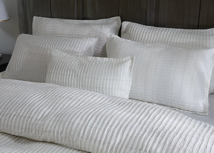 Close-up of off-white striped duvet cover and square pillows