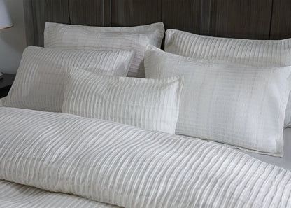 Close-up of off-white striped duvet cover and square pillows
