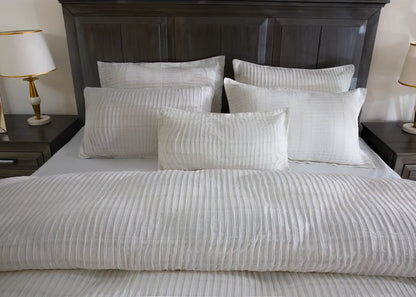 Off-white striped duvet cover with multiple matching pillows on bed