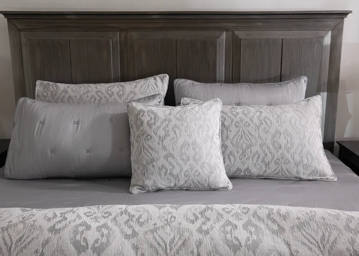 Grey duvet cover and patterned pillow shams with decorative pillows, close-up on bed