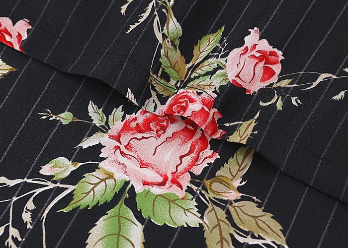Close-up of black floral cotton bed sheet fabric with red roses and green leaves