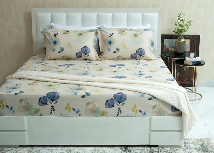 Cream cotton bed sheet with blue and yellow floral pattern, laid across the mattress