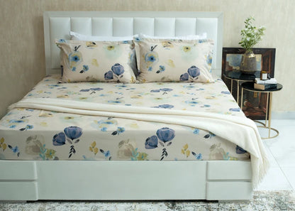 Cream cotton bed sheet with blue and yellow floral pattern, laid across the mattress