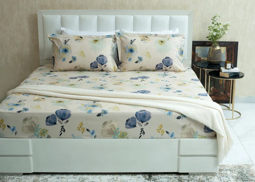 Cream cotton bed sheet with blue and yellow floral pattern, laid across the mattress