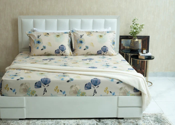 Cotton cream bed sheet set with blue and yellow floral print, neatly folded on a bed