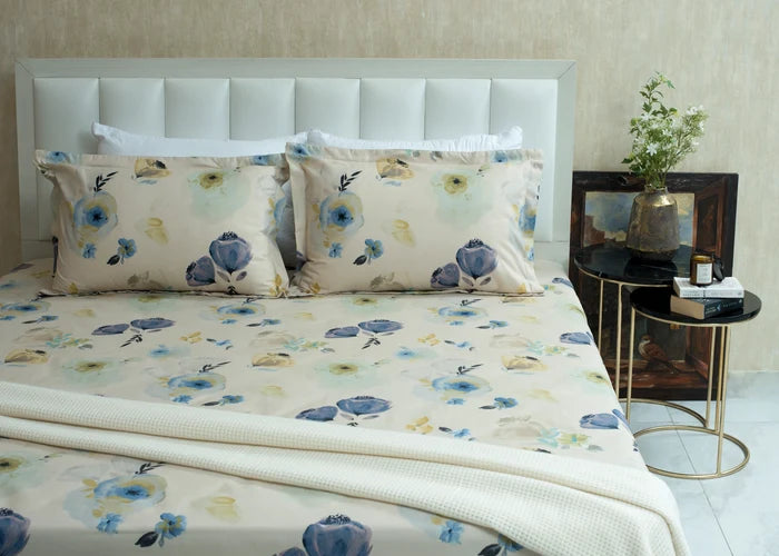 Cream cotton bed sheet with blue floral and botanical print, showing quilted texture edge