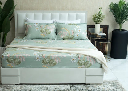 Light green tropical floral bed sheet on neatly made bed with matching pillows