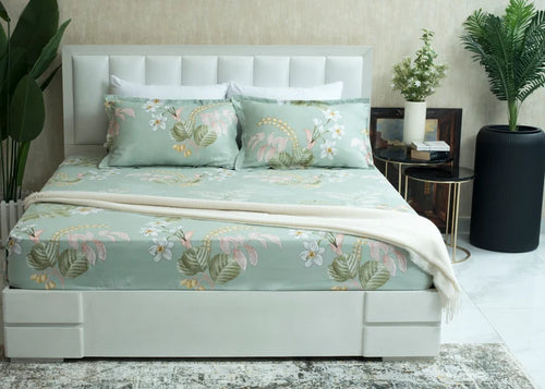 Light green tropical floral bed sheet on neatly made bed with matching pillows