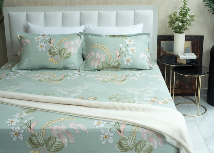Light green tropical floral bed sheet with leaf and flower print, neatly draped