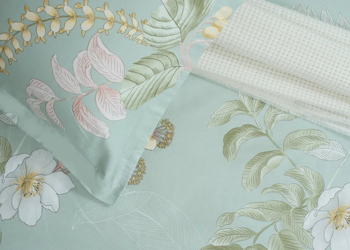 Light green tropical floral bed sheet fabric close-up with leaf and blossom print