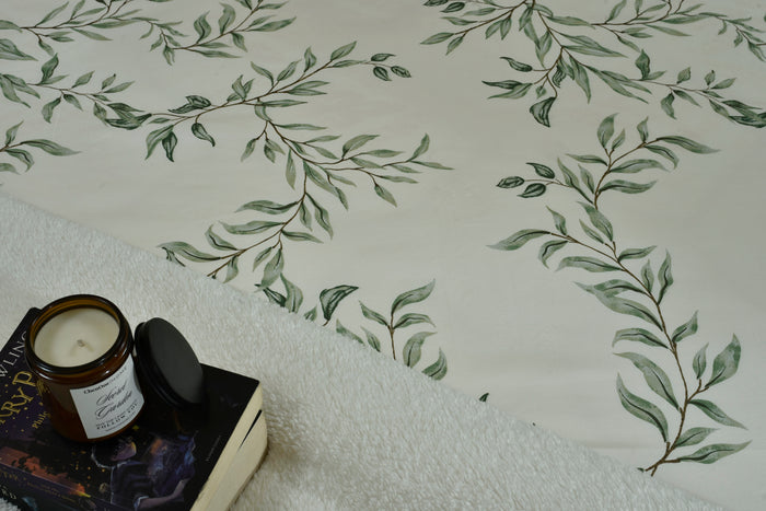 Leaf-print cotton sateen top sheet corner with off-white fabric and green branch pattern