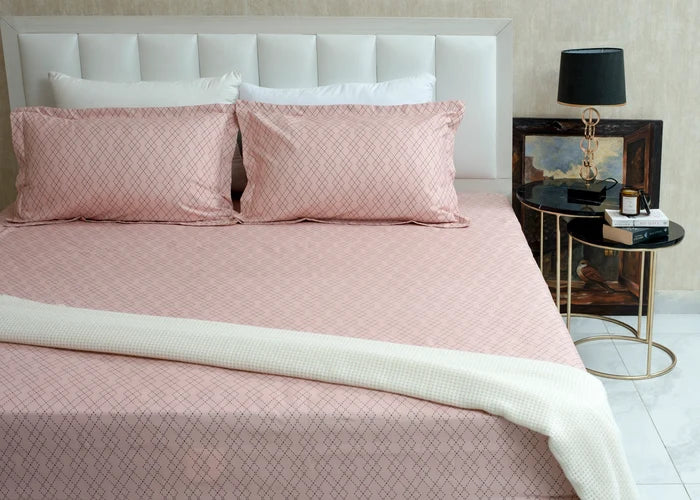 Pink diamond-pattern bed sheet with matching pillowcases on a made bed