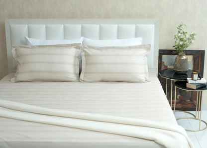 Single beige cotton bed sheet set with two pillow shams, neatly laid on the bed