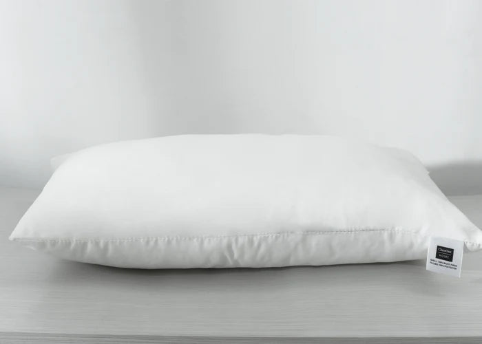 White rectangular compressed pillow with front-facing label tag at lower right
