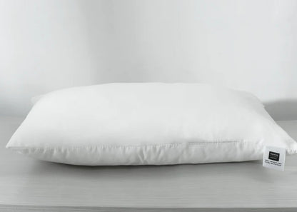 White rectangular compressed pillow with front-facing label tag at lower right