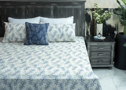White cotton bed sheet with blue botanical pattern, neatly styled on the bed with pillows