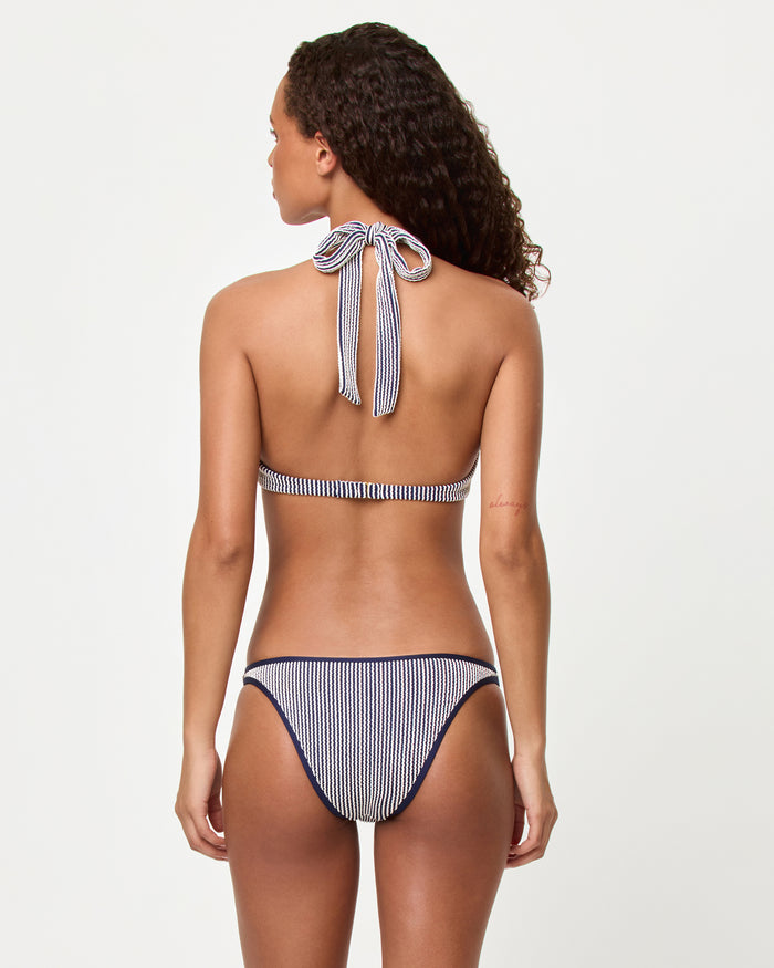 Back view of a model wearing the LSPACE midnight blue Isa Bikini Top and Suzi Bikini bottom showing the halter neck tie and band back closure in navy stripe.