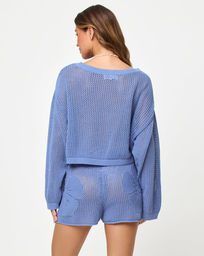 Back view of a model wearing the LSPACE Island Time Short in Chambray, styled with the matching Island Time Sweater, showing the floral crochet pattern and open-knit construction.