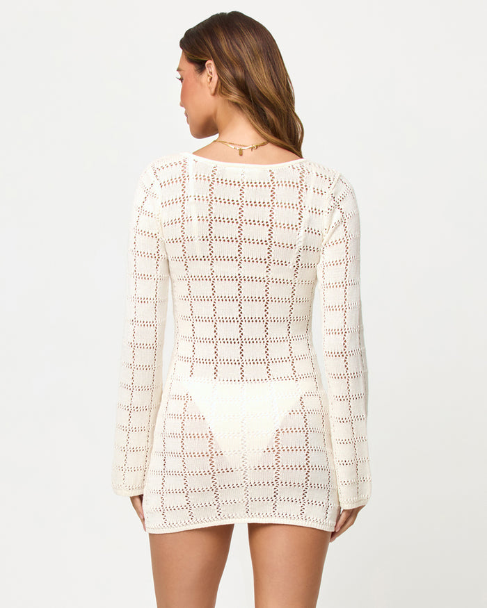 Back view of a model wearing the LSPACE Jessa Mini in cream on a white background, showing the open-knit crochet construction and long sleeves.