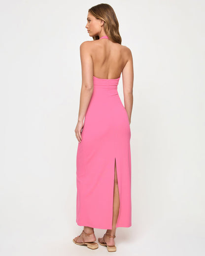 Back view of a model wearing the LSPACE La Femme Dress in begonia, showing the low open back, halter neck tie, and back slit at the hem.