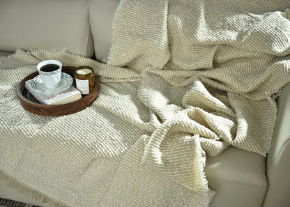 Light taupe knitted throw blanket close-up with textured knit and fringe trim
