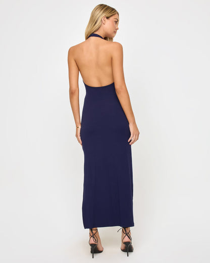 Back view of a model wearing the LSPACE London Dress in midnight blue, showing the open-back halter design with a tie neck closure.