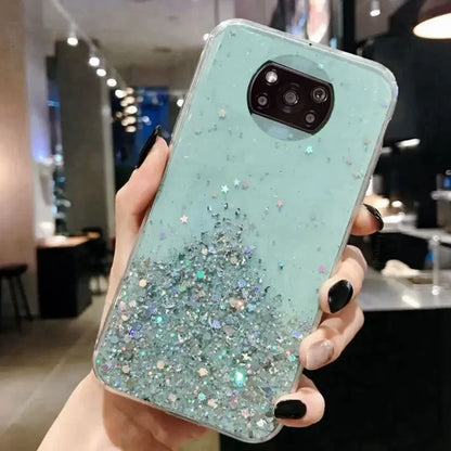 a woman holding up a phone case with glitter