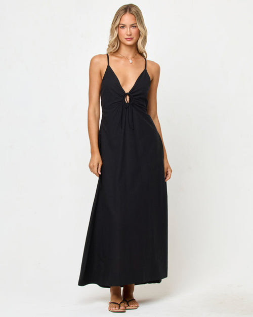 Front view of a model wearing the LSPACE Mabel Maxi Dress in black, featuring thin spaghetti straps, a deep V-neckline with ring hardware detail, and a flowing A-line maxi skirt.