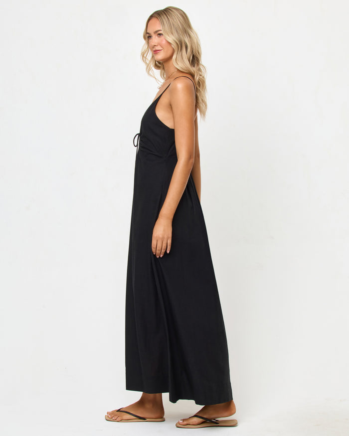 Side view of a model wearing the LSPACE Mabel Maxi Dress in black, showing the deep V-neckline, spaghetti straps, and flowing A-line silhouette.