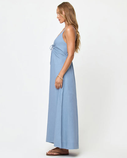Side view of a model wearing the LSPACE Mabel Maxi Dress in chambray, showing the deep V-neckline, ring detail, and flowing A-line maxi silhouette.